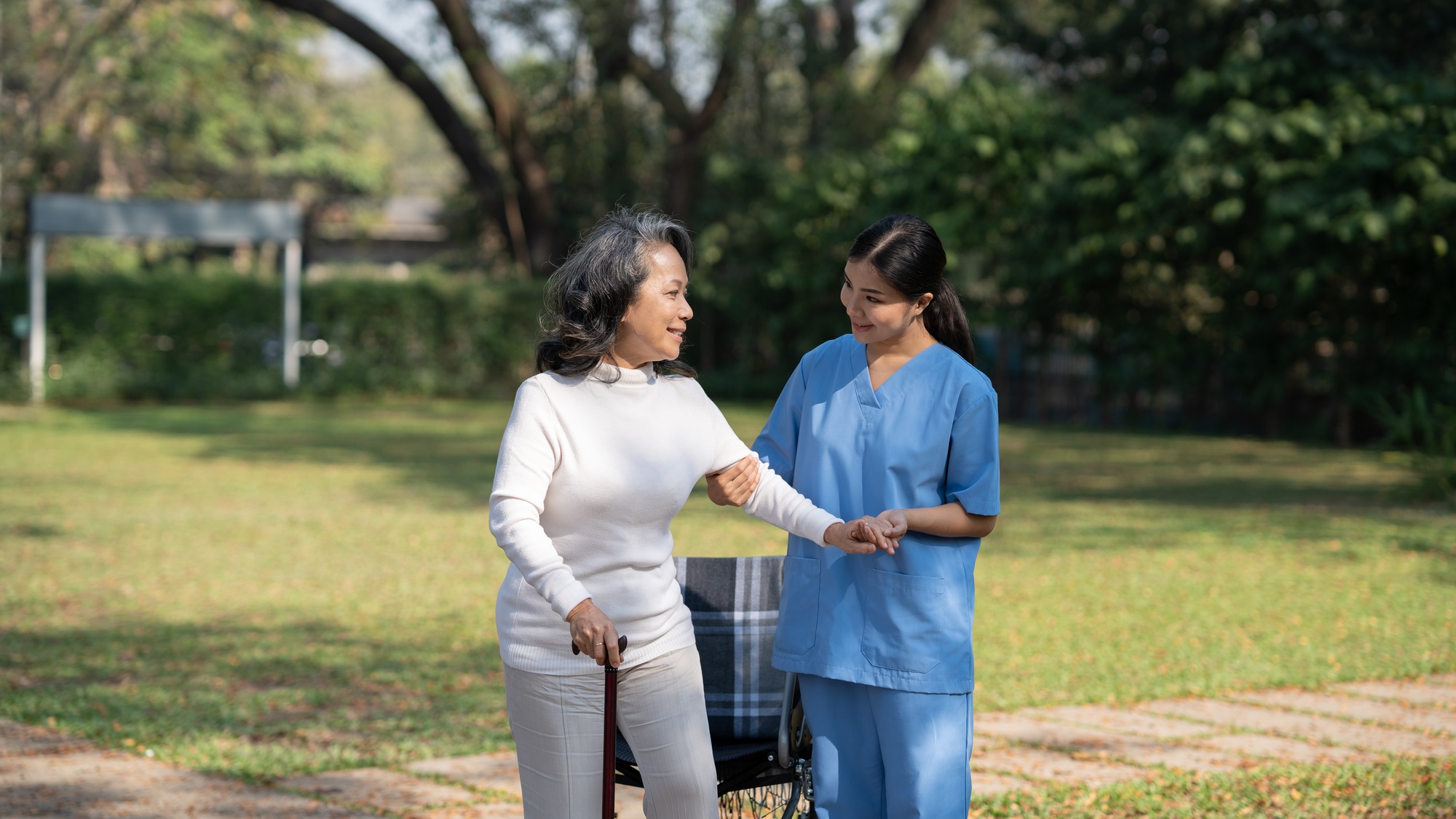 Old lady smiling at her nurse while the nurse is taking care of her. Professional nurse assistant